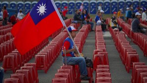 A voter holds a Taiwan flag as he waits for the start of a campaign rally