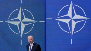 US President Joe Biden stands in front of the NATO logo