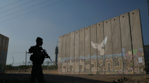 A member of the Israeli forces stands next to a wall with Hebrew writing reading "Path to Peace" at the Kibbutz Netiv Haasara near the border with Gaza Strip, Israel on November 17, 2023.