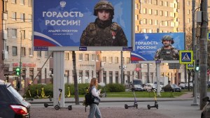 A woman walks past advertising billboards which show Russian soldiers