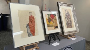 Three framed color drawings sit on a gray table